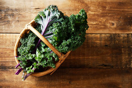 Green and purple leaves of Kale in a basket on a small table Organic vegetables. Healthy food.の写真素材