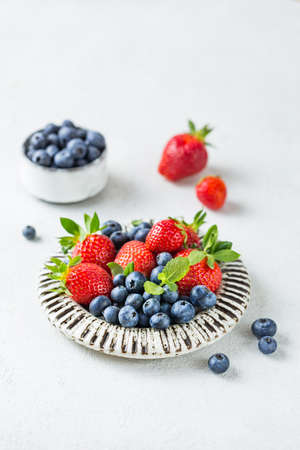 Ripe red strawberries and blueberry on a plateの写真素材