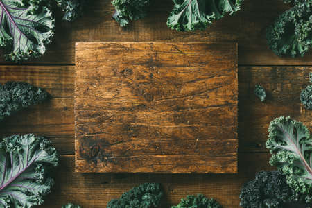 Empty cutting Board and Kale leaves on a wooden background. Clean food. Healthy product. Top view, Copy spaceの写真素材