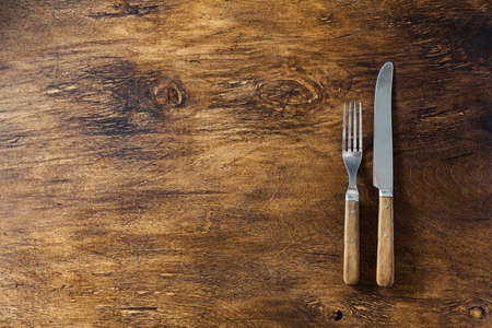 Cutlery with wooden handles on a wooden surface, top view.の写真素材