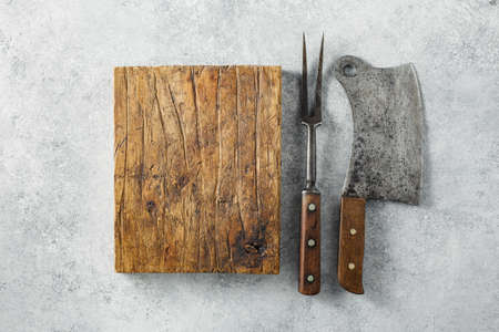 Vintage Meat cleaver and BBQ fork and empty wooden cutting boardの写真素材