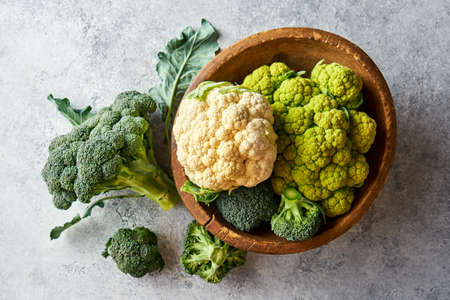 Fresh cabbage broccoli and cauliflower in a wooden bowl, Top view.の写真素材