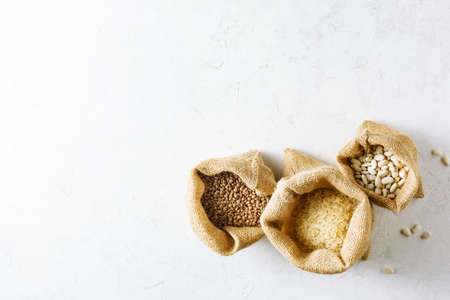 Rice, lentils and white beans in canvas bags on whiteの写真素材