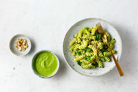 Fusilli with green pesto sauce, broccoli and cashew nuts. Top view.の写真素材