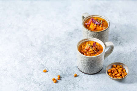Sweet potato soup with bacon, crispy chickpeas and red onions. Copy space.