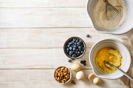 Ingredients for baking muffins with blueberries and almonds on a wooden table with copy space. Top view.の写真素材