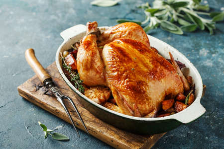 Whole roasted chicken with vegetables on wooden cutting boardの写真素材