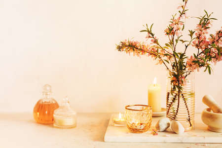 Scented candles, essential oils, marble mortar and wild almonds flowers on a table.の写真素材