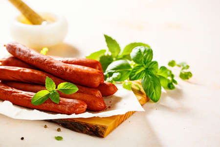 Delicious homemade sausages with spices and basil, on a chopping board.の写真素材