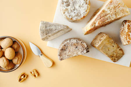 Various pieces of aged cheeses on a board and walnutsの写真素材