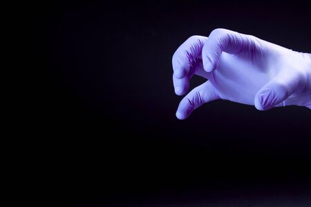A purple claw in medical glove scares virus on a black backgroundの写真素材