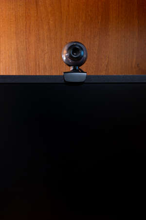 External round black web camera on a black monitor. Webcam on a wooden background.の写真素材