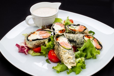 warm Japanese salad with fish and greens with sauce on a white plate, isolated black backgroundの写真素材