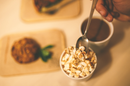 cocoa with marshmallows and cake on the table. Hand mixed drink. Wooden table, metal spoonの写真素材