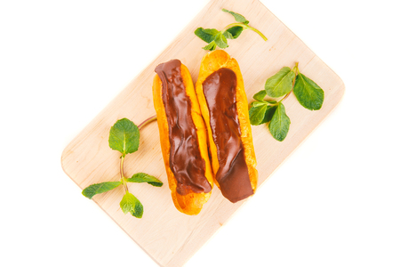 custard cake, Eclair with chocolate and cream dessert on a wooden plate, white background, mint