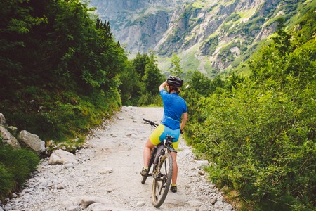 girl on a Bicycle travels to Slovakia. black helmet, blue shirt, mountains, high Tatras, Sunny weatherの写真素材