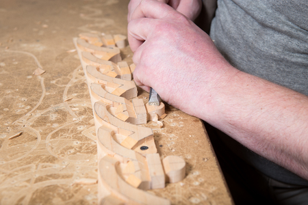 Artisan woodcarver creates a furniture ornament. Woodcarver's hands, chisels, tools, wood-carved...