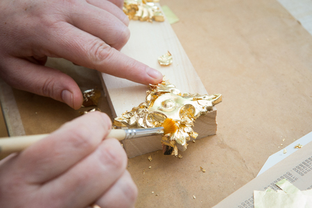 female hand painting with a brush baguette for ceiling and walls in gold colorの写真素材