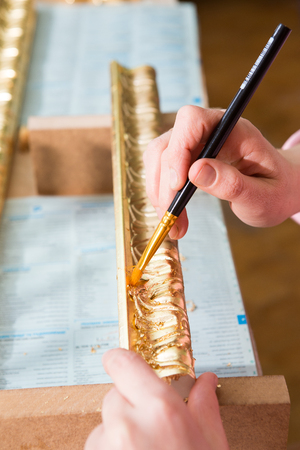 female hand painting with a brush baguette for ceiling and walls in gold colorの写真素材