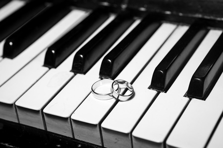 Wedding rings on piano black and whiteの写真素材