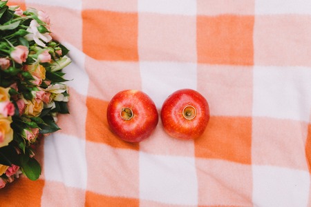 Red apples and wedding rings on a plaid blanket near the wicker basketの写真素材