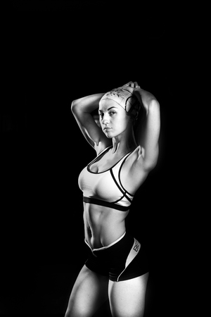 beautiful, sexy, athletic girl standing with hands raised up in the gym. Dressed in shorts and a t-shirt with a bandage on his head. Sports concept.の写真素材
