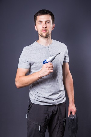 Man holding an electric construction tool in his hands against a dark backgroundの写真素材