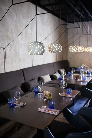 Glasses, flower fork, knife served for dinner in restaurant with cozy interior