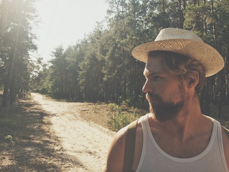 Portrait of a man in a hat with a blurred Against the background of coniferous forest