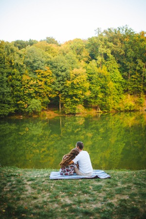 Beautiful loving couple sitting embracing by the lakeの写真素材