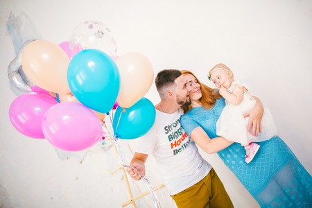 a young family of three people, mom's dad and daughter's one year old stands inside the room in...
