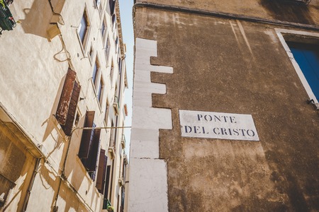 Beautiful view of a picturesque narrow alley with historic traditional houses and cobbled streets in the old city in Europe with blue sky and clouds in summer in Italy Venice.の写真素材