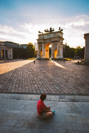 girl tourist looking atArch of Peace in Sempione Park, Milan, Lombardy, Italy. Arco della Pace aka Porta Sempione in Milan, Italy.の写真素材