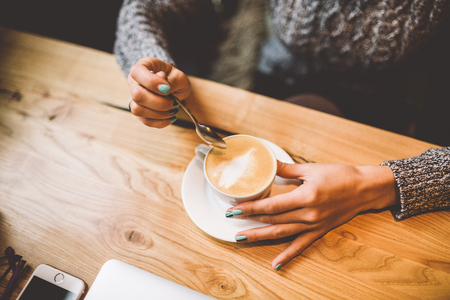 beautiful business girl drinking coffee from white cup in restaurant decorated with Christmas...