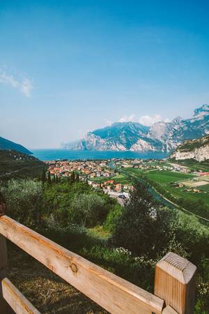 Beautiful panorama view of a mountain lake in northern Italy in the lombardy of lago di garda from a birds eye view. View of the roofs of the city and the channel of Riva del Garda in summer.の写真素材