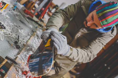 Male worker repairing Stone, edge sharpening in ski service workshop, sliding surface of the skis. sharpening of an edging of a mountain skis by means of the individual tool. Theme repair of ski curb.の写真素材