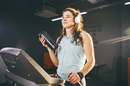 Sports nutrition and exercise. beautiful woman holds protein in her hand in bottles, shaker, listens...