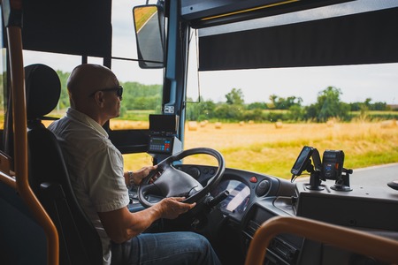Theme is the profession of the driver and passenger transportation. A man in sunglasses A driver drives a tourist regional bus in the france region of the burgundy in summer.のeditorial素材