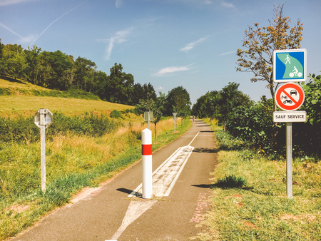 Transport and roads in the france region of the burgundy. Bicycle route, service road in rural areas in summer. Road signs and warnings in Europe. Cyclist man riding a bicycle road.の写真素材