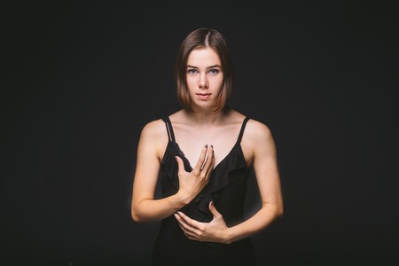 Portrait of a beautiful young Caucasian Caucasian woman 20 years old model with blue eyes natural make-up of hair on shoulder dancing hands posing on black isolated background in black lingerie.の写真素材