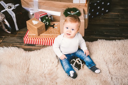 theme winter and Christmas holidays. Child boy Caucasian blond 1 year old sitting home floor near...