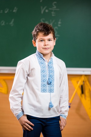 Portrait of a schoolboy. Young 10 years old caucasian boy posing in a school class standing against a green school board. Theme Collegeのeditorial素材