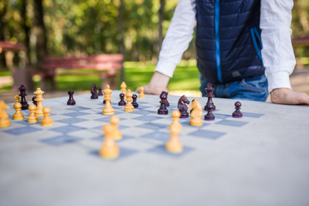 The topic is children learning, logical development, mind math, miscalculation moves advance. Big family two brothers Caucasian boys playing chess in the park in bright sunny weather in the autumn.の写真素材