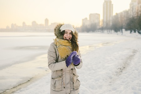 Portrait of a beautiful young Caucasian woman in a knitted hat and scarf standing on a winter...
