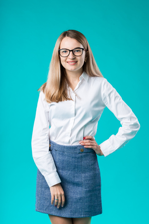 Blank for advertising. Portrait young caucasian woman worker teacher coach mentor in white shirt office style business lady leader advertising glasses eyesight blue isolated color background.の写真素材
