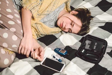 Theme diabetes. young caucasian woman at home in the bedroom on the bed uses the technology of the...