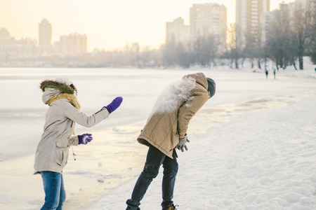 Young Caucasian people in love heterosexual couple have a date in winter near a frozen lake. Active holiday holiday Valentine's Day, playing snowballs and playing joy.の写真素材