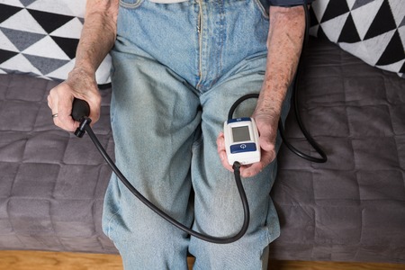 The topic is very old person and monitor health. Hands close-up macro close up Senior Caucasian woman uses electronic monitor technology tonometer to check blood pressure.の写真素材