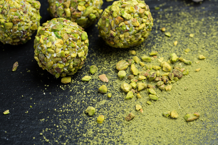 Theme sweet dessert cake handmade. Macro close-up dessert dessert sweet candy round ball white truffle ball set of white chocolate, matcha tea and pistachios on a black background.の写真素材