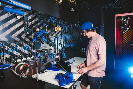 Theme business profession manager and technology. Young stylish Caucasian male owner bicycle shop uses a laptop computer near the stand with the tools for repairing and servicing the bicycle.の写真素材